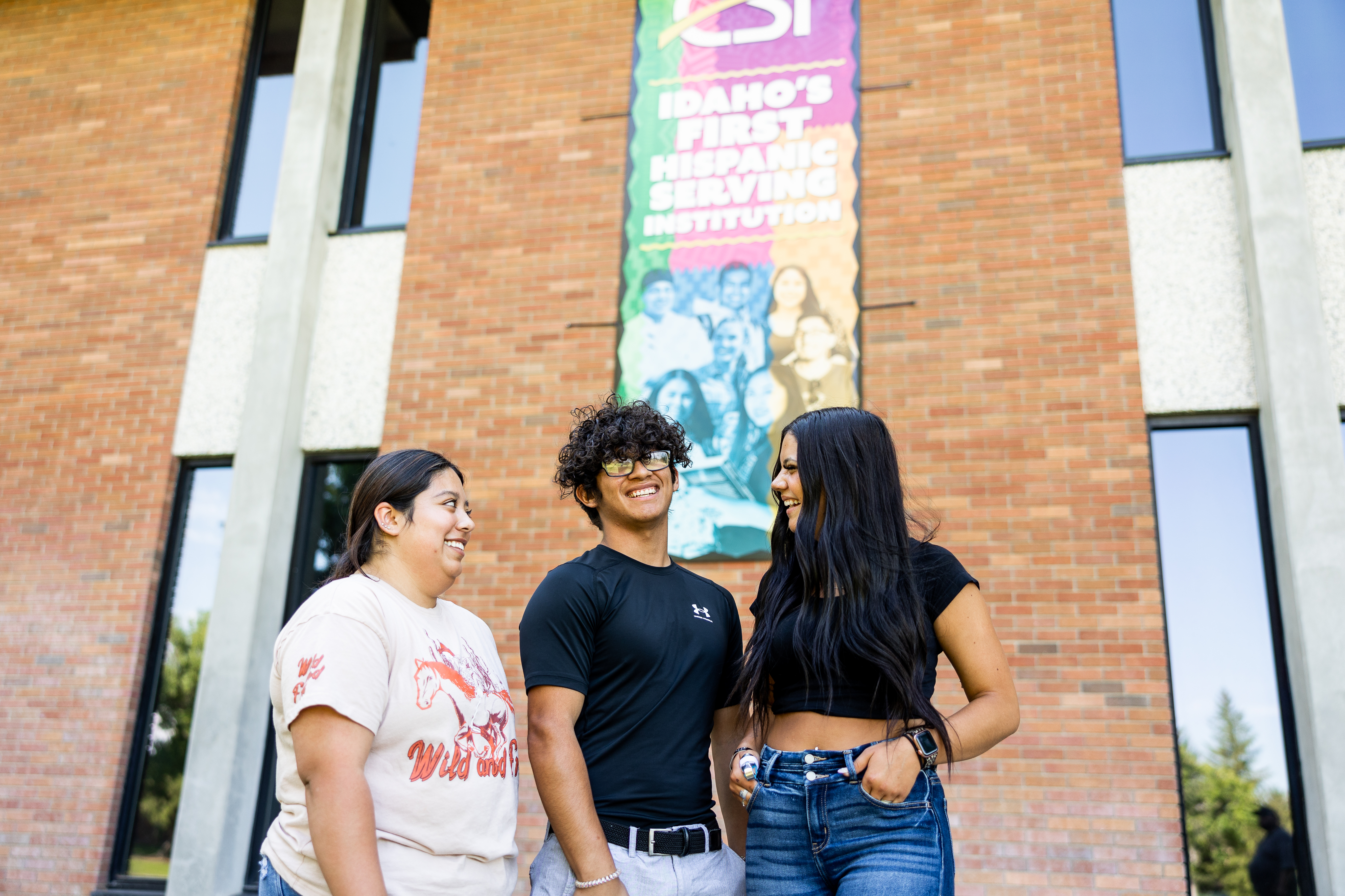 Three students standing together in front of the CSI Shield's building