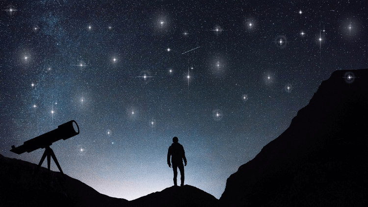 Man looking at the night sky between two mountains